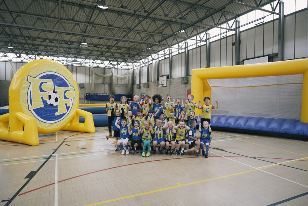 Happy group of children at Football Fun Camps - a holiday activity for kids involving giant football inflatables.