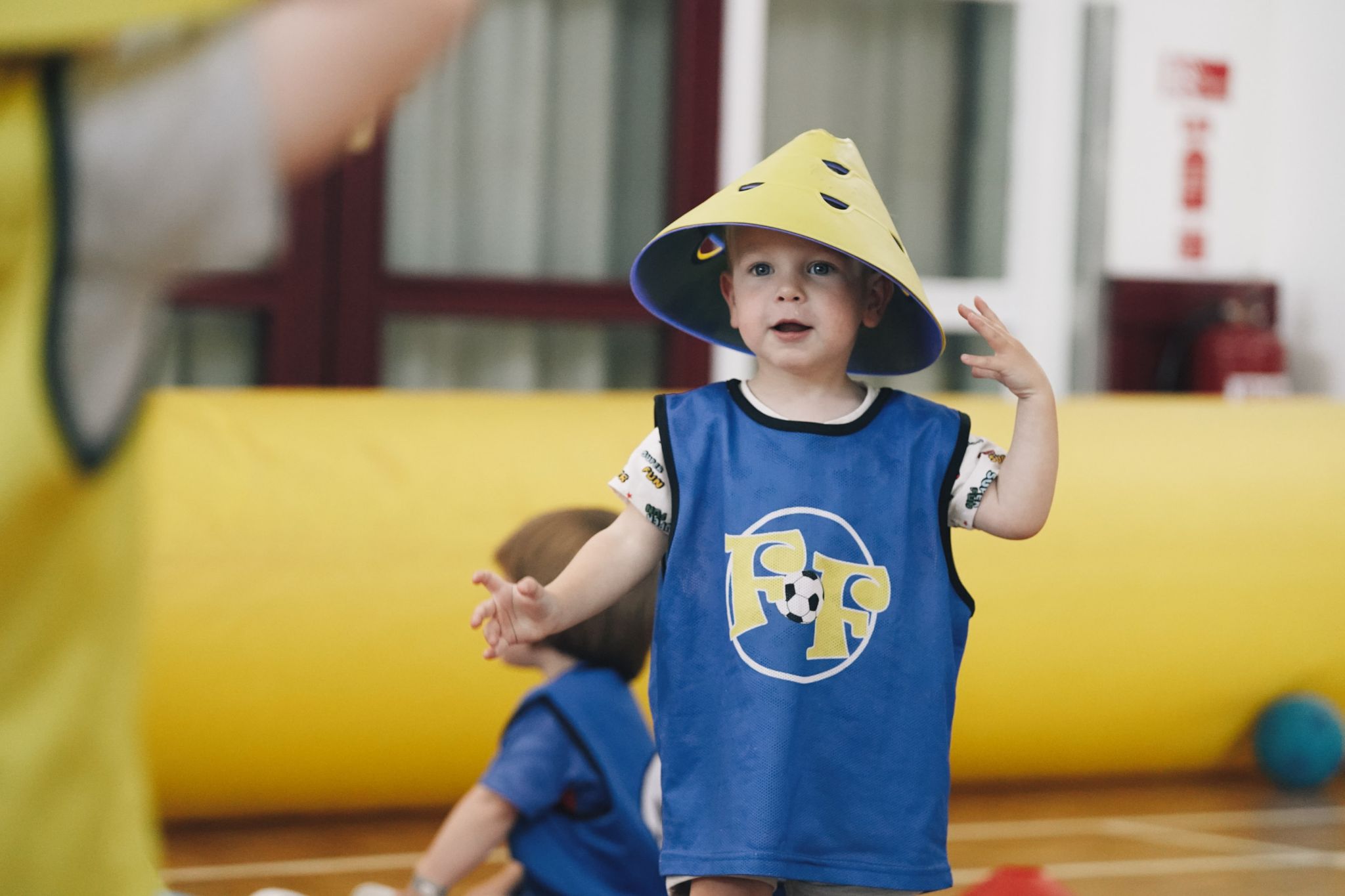 A toddler at Football Fun Factory, wearing a cone on his head