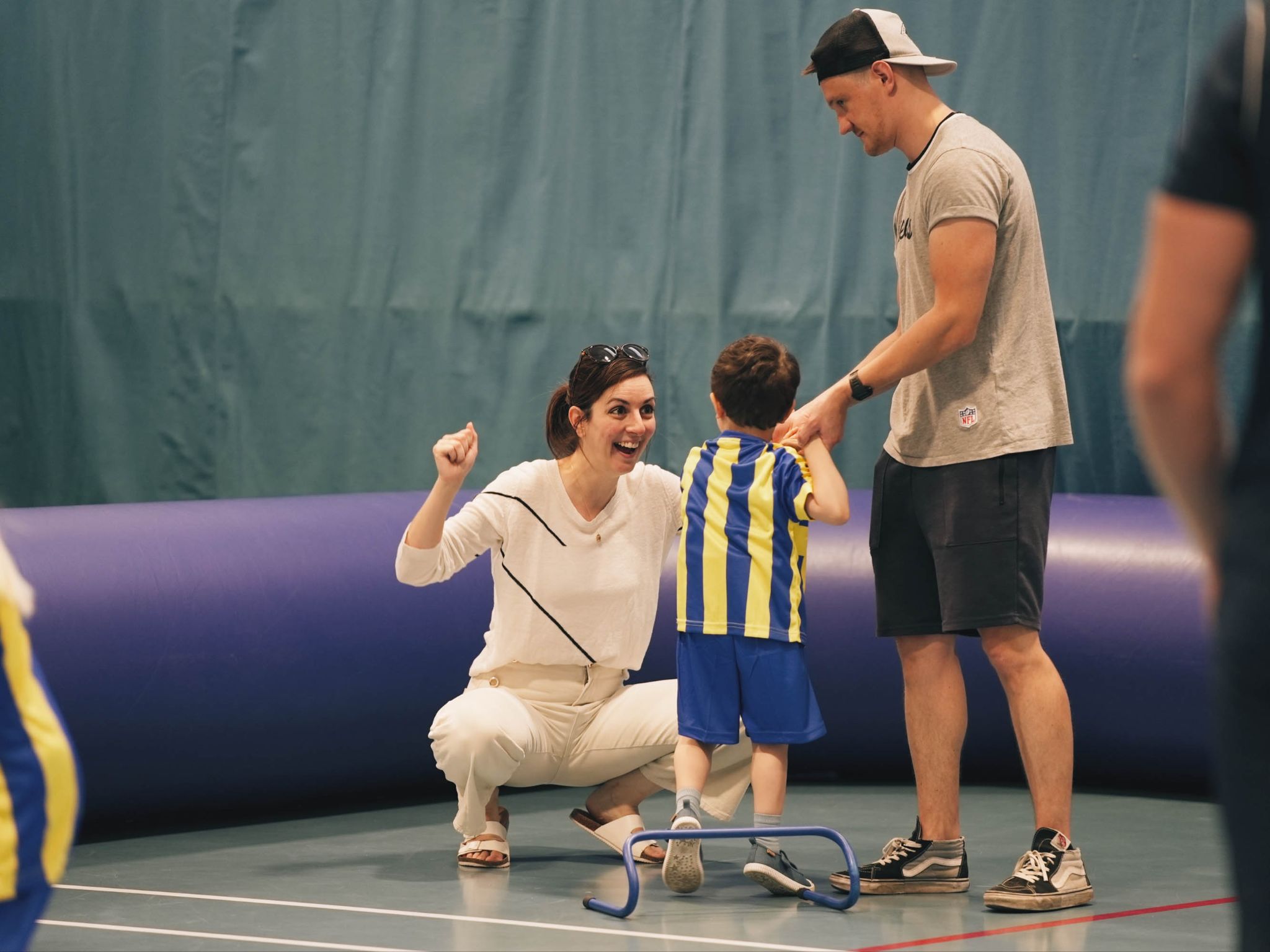 A mother and father cheering on their toddler at a Football Fun Factory session 