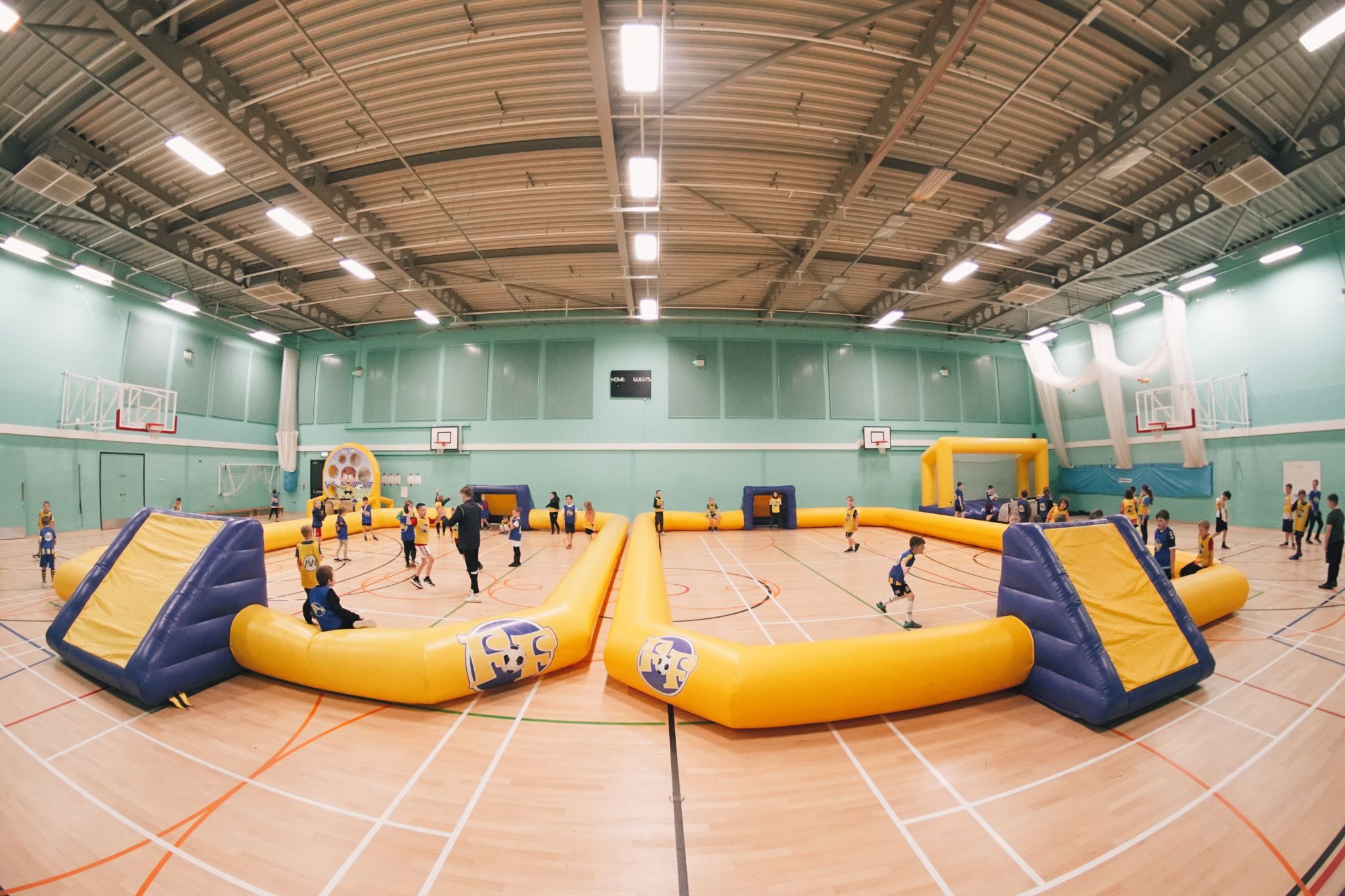 A wide angle shot of a Football Fun Factory camp, with inflatables pitches with children playing football